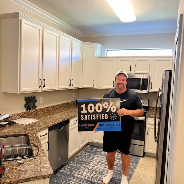 Customer holding a 100% Satisfied sign in a white kitchen