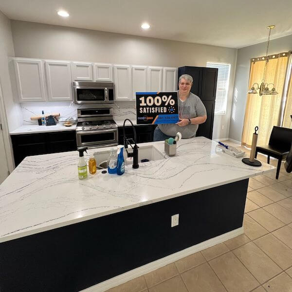 Customer holding a 100% Satisfied sign in a two-tone kitchen