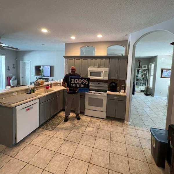 Customer holding a 100% Satisfied sign in a greige kitchen
