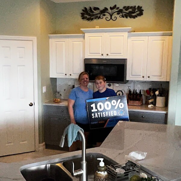 Customer holding a 100% Satisfied sign in a finished kitchen